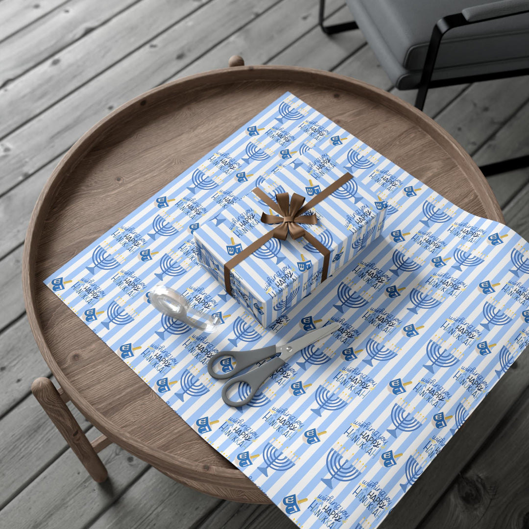 Blue striped wrapping paper with Wishing you a happy Hanukkah text, a graphic of a menorah and dreidel in a varied pattern!