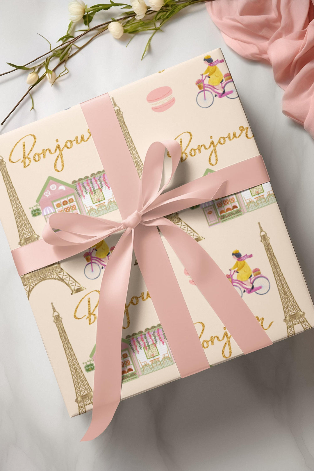 Elegant Paris themed wrapping paper in beige with super cute and fun graphics of a gold Eiffel Tower, adorable French bakery that has florals on the roof of it, &quot;bonjour&quot; text, woman riding her bicycle, pink macaroon