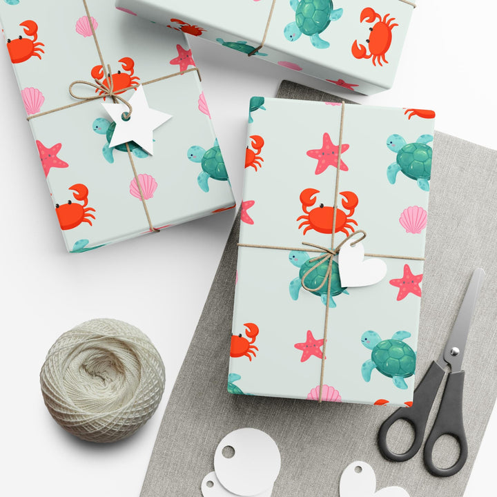 off white background with cute graphics of smiling sea creatures-sea turtle, crab, starfish, pink seashell on wrapping paper!