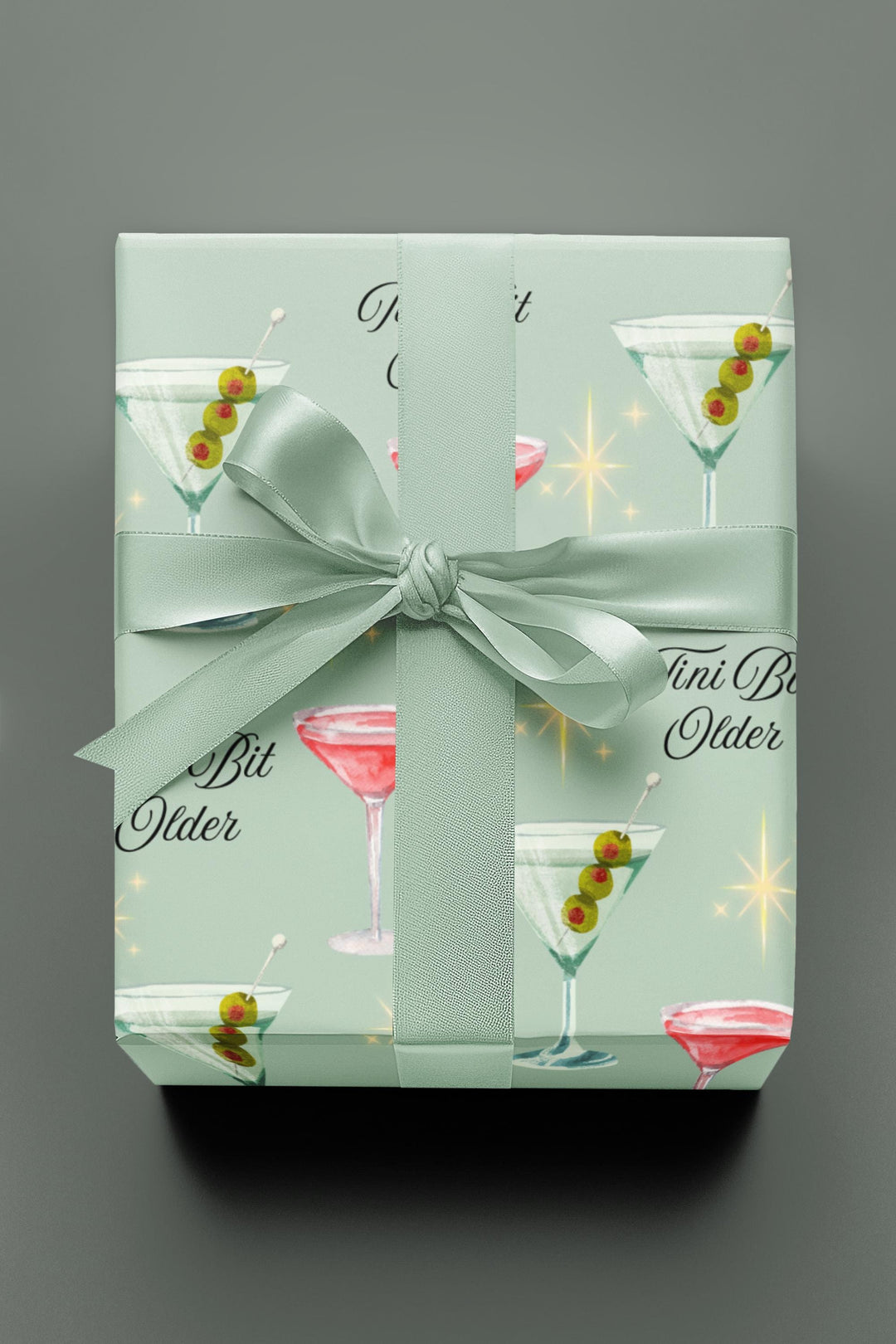 Green wrapping paper with martini glasses and Tini Bit Older text