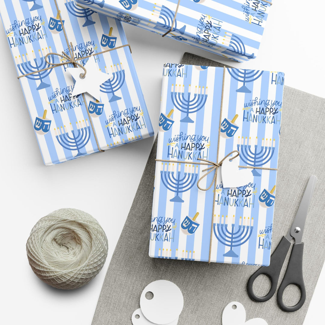 Blue striped wrapping paper with Wishing you a happy Hanukkah text, a graphic of a menorah and dreidel in a varied pattern!