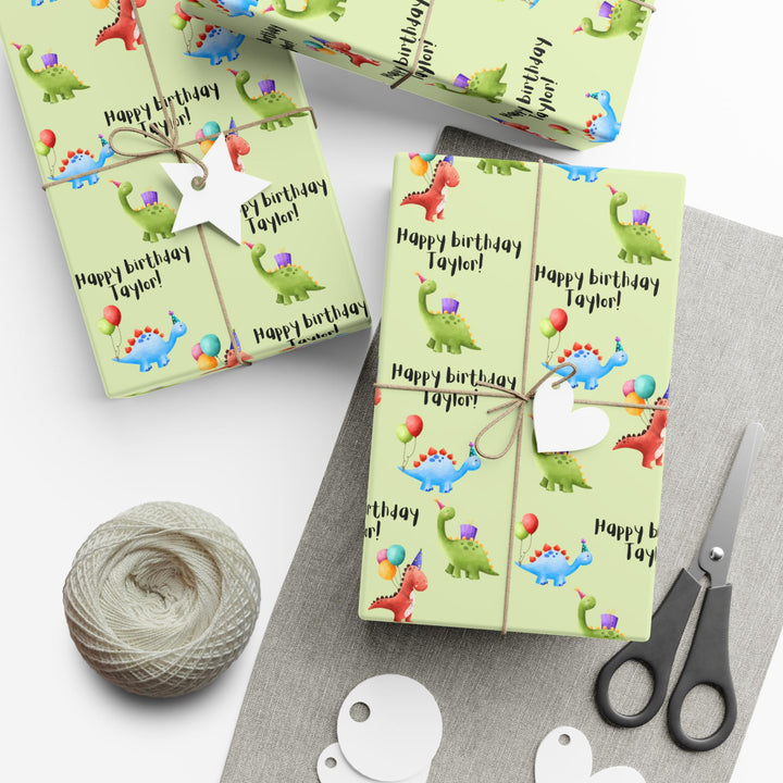 Green wrapping paper with dinosaur fun cute graphics with birthday hats and balloons and personalized happy birthday text