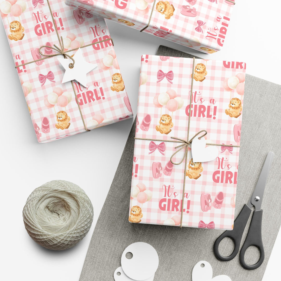 Pink gingham wrapping paper with graphics of lion with balloons, baby ballet flats, baby pink bow and It&#39;s a Girl text