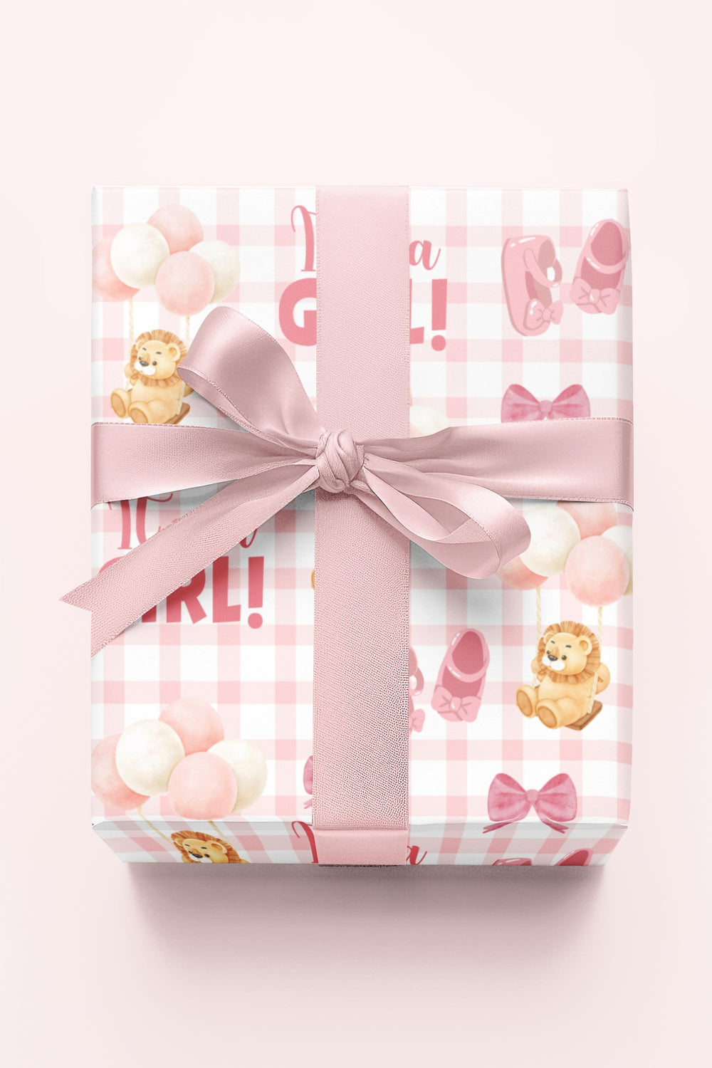 Pink gingham wrapping paper with graphics of lion with balloons, baby ballet flats, baby pink bow and It's a Girl text