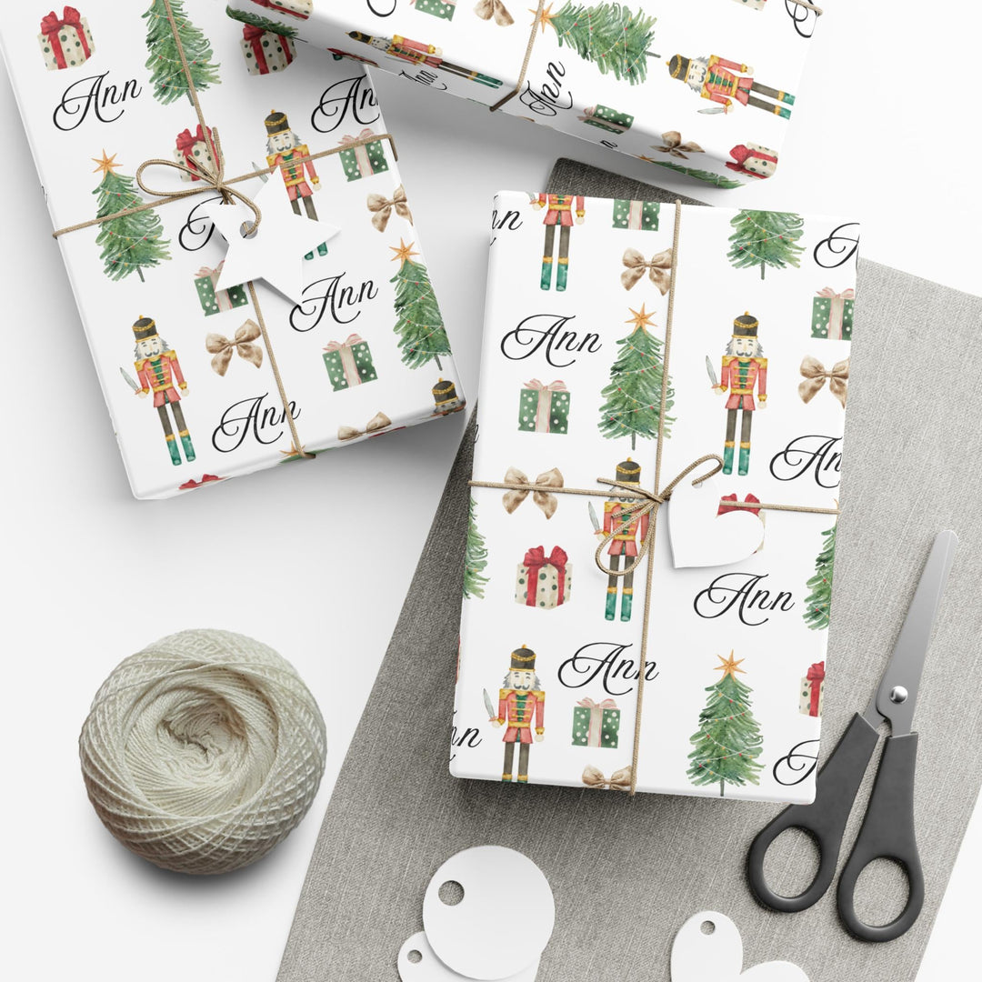 wrapping paper with white background and graphics of a nutcracker, christmas tree, christmas present, bow, and script text with a personalized name