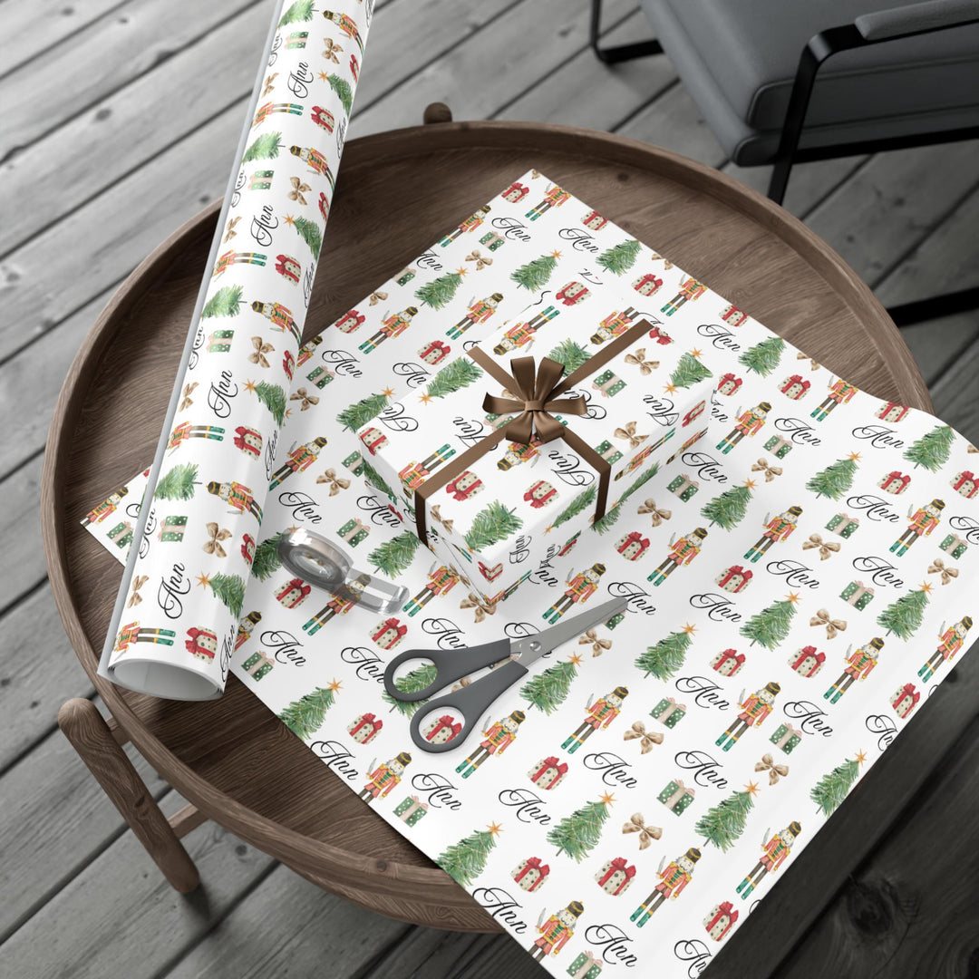 wrapping paper with white background and graphics of a nutcracker, christmas tree, christmas present, bow, and script text with a personalized name