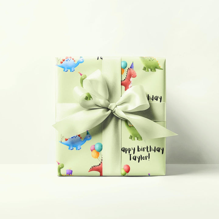 Green wrapping paper with dinosaur fun cute graphics with birthday hats and balloons and personalized happy birthday text