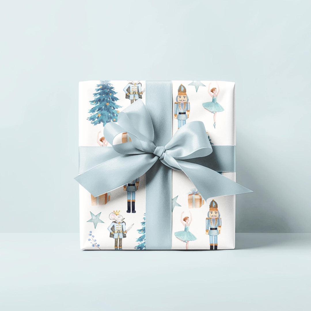 christmas theme wrapping paper blue graphics of a blue christmas tree, blue ballerina, blue nutcracker, blue mouse nutcracker graphic, blue star, blue present, blue florals on a white background