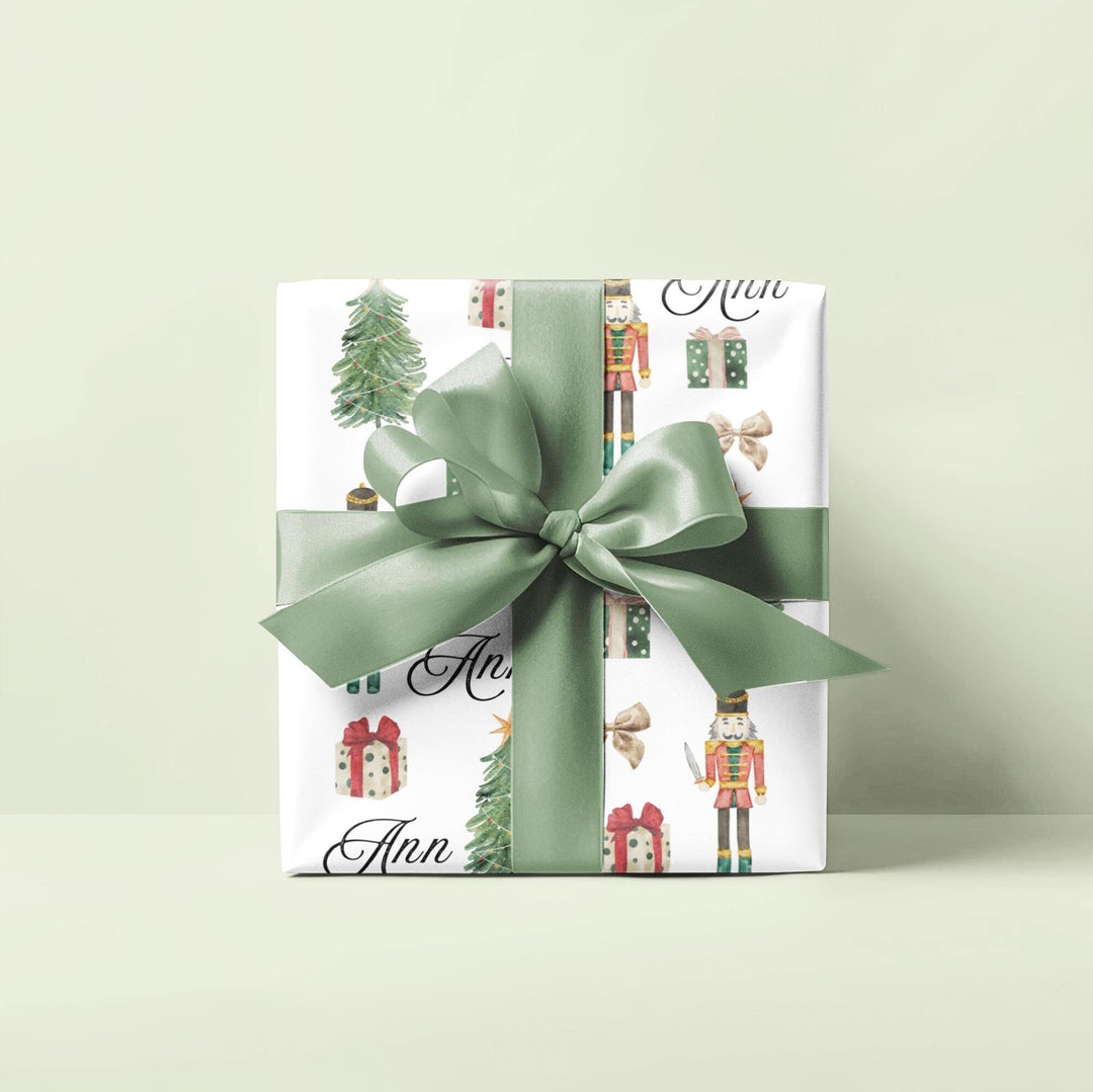 wrapping paper with white background and graphics of a nutcracker, christmas tree, christmas present, bow, and script text with a personalized name