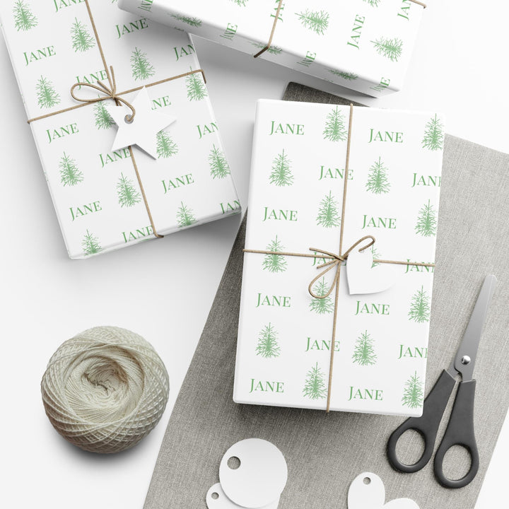 white background with elegant green christmas trees and display font of a personalized name on wrapping paper