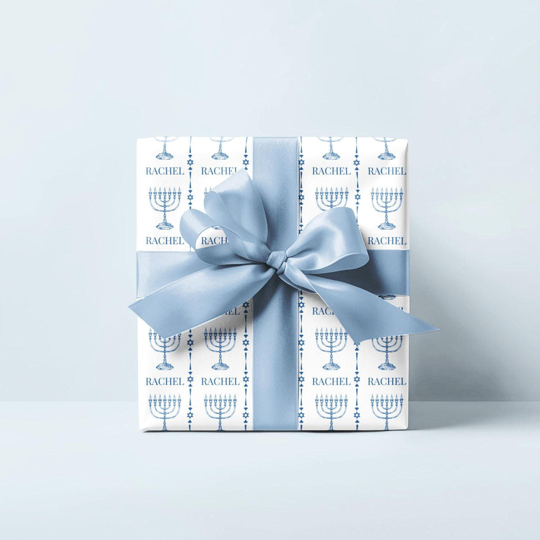 white wrapping paper with blue menorahs and traditional Jewish symbols and personalizable with a name in blue text